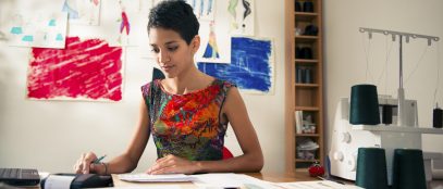 Money and financial planning, young hispanic self-employed woman checking bills and doing budget with calculator, computer and papers in fashion design studio