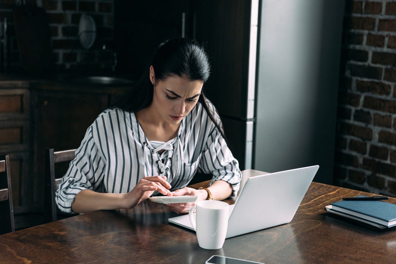 Young woman with calculator and laptop counting money