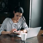Young woman with calculator and laptop counting money