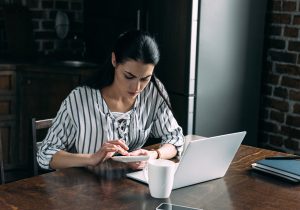 Young woman with calculator and laptop counting money