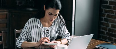 Young woman with calculator and laptop counting money