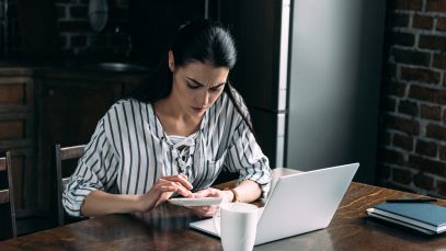 Young woman with calculator and laptop counting money