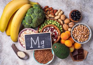 A small sign with the periodic symbol, Mg, written in chalk sits on top of a collection of magnesium-rich food.