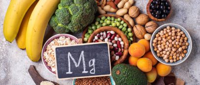 A small sign with the periodic symbol, Mg, written in chalk sits on top of a collection of magnesium-rich food.