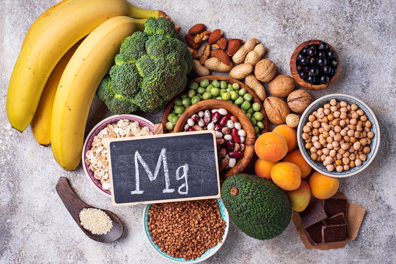 A small sign with the periodic symbol, Mg, written in chalk sits on top of a collection of magnesium-rich food.