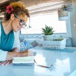 A woman enjoying the joys of simple living in her solo travels, taking notes in a notebook.