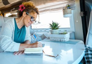 A woman enjoying the joys of simple living in her solo travels, taking notes in a notebook.