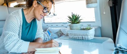 A woman enjoying the joys of simple living in her solo travels, taking notes in a notebook.