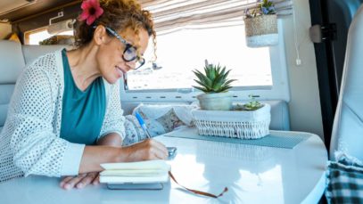 A woman enjoying the joys of simple living in her solo travels, taking notes in a notebook.