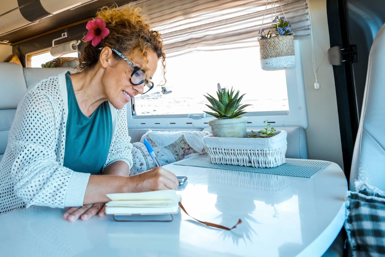 A woman enjoying the joys of simple living in her solo travels, taking notes in a notebook.