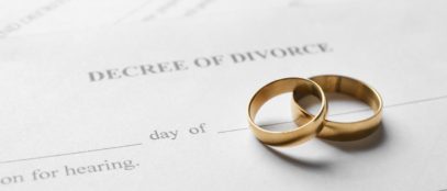 A paper that reads “decree of divorce” with two gold wedding bands stacked on each other resting on top of it.